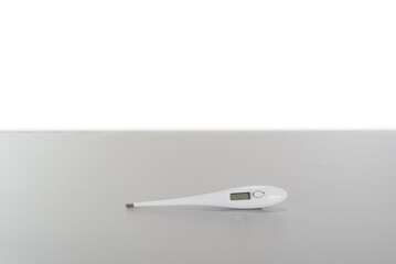 white digital thermometer lying on a gray table with copy space background