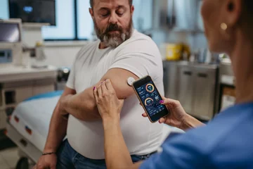 Fotobehang Doctor connecting continuous glucose monitor with smartphone, to check blood sugar level in real time. Obese, overweight man is at risk of developing type 2 diabetes. Concept of health risks of © Halfpoint