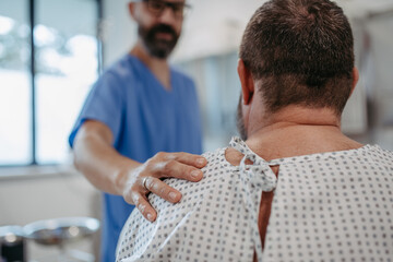 Supportive doctor soothing a worried overweight patient, discussing test result in emergency room. Illnesses and diseases in middle-aged men's health. Compassionate physician supporting stressed - obrazy, fototapety, plakaty