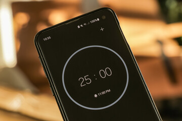 A phone with a black and white 25-minute timer to study with the pomodoro method on a blurry...
