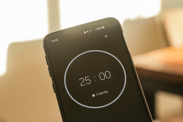 A phone with a black and white 25-minute timer to study with the pomodoro method on a blurry...