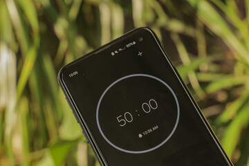 A phone with a black and white 50-minute timer to study with the pomodoro method on a blurry...