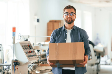 In the glasses. Handsome man is working at the factory of creating eco boxes