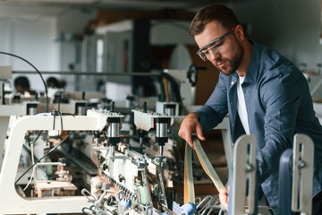 Skilled engineer. Handsome man is working at the factory of creating eco boxes