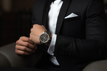  A trendy young adult makes a style statement by pairing a minimalist watch with a formal outfit, exemplifying modern elegance