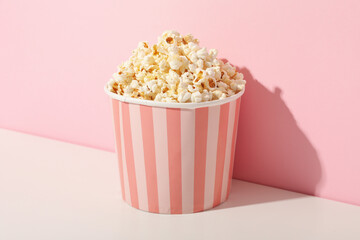 Popcorn in pink paper bag on pink background