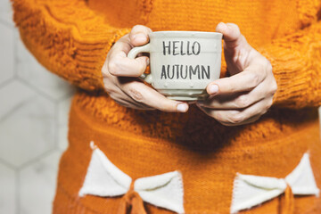 woman wearing winter clothes and holding a cup of coffee with hello autumn concept 