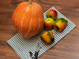 Close up shot of the pumpkin, capsicums and apples on the wooden table. Holiday