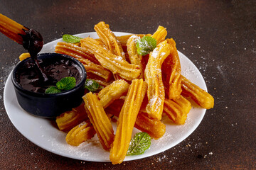 Traditional Spanish dessert churros with sugar powder and chocolate sauce