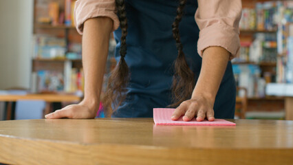 Close-up unrecognizable woman barista waitress in apron wipe table in cafe girl lady catering worker wiping cleaning restaurant clean prepare cafeteria for visitors treat surface from bacteria hygiene