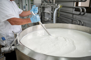 worker's hands during the process of making cheese from milk