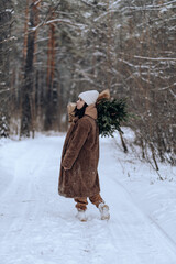 a girl with a bouquet of fir branches walks through the winter forest