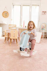 Toddler baby playing on the rocking bike in the kindergarten