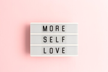 More self love. White lightbox with letters on a pink background. - obrazy, fototapety, plakaty