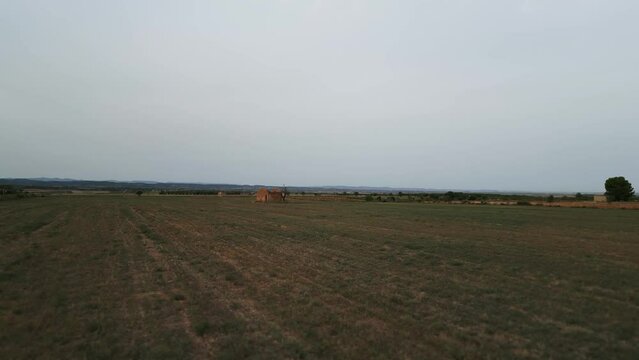 Aerial low flying over field in Tarrega, Spain, passing by traditional tool shed