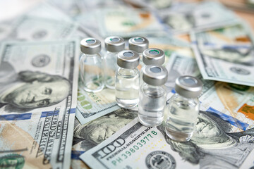  COVID-19 or other vaccine in bottle on dollar bills background