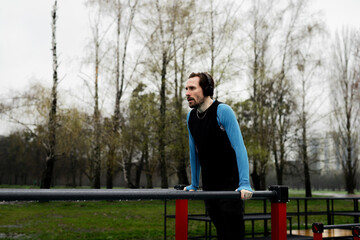 Sportsman sets a record for pushups parallel bars. Concentrated man listen music headphones while...
