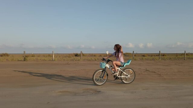 Long red hair girl riding a bike in street a sunny desert countryside. Spain