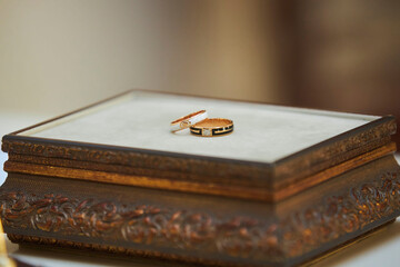 Two wedding rings lying on a wooden box on the table next to the handle. Preparation for the wedding ceremony