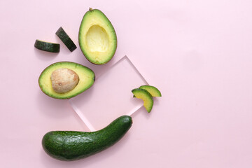 On the pastel pink background, transparent glass podiums decorated with fresh avocado slices. The concept of organic natural cosmetics with avocado extract. Copy space.