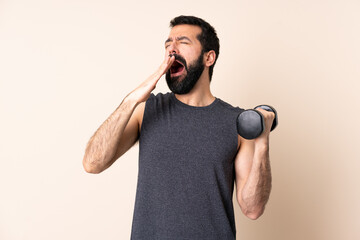Caucasian sport man with beard making weightlifting over isolated background yawning and covering wide open mouth with hand