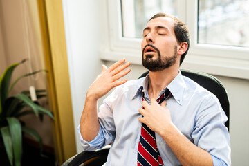 Nervous businessman working in a very hot office, he is sweating and loosening his tie