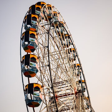 Closeup of multi-coloured Giant Wheel during Dussehra Mela in Delhi, India. Bottom view of Giant Wheel swing. Ferriswheel with colourful cabins during day time.