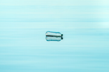 Empty plastic bottle floating on water, environmental damage and pollution concept