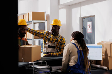 Mail processing center warehouse workers giving parcel to dispatching manager at reception. African american storehouse men employees putting prepared customer order package at counter desk