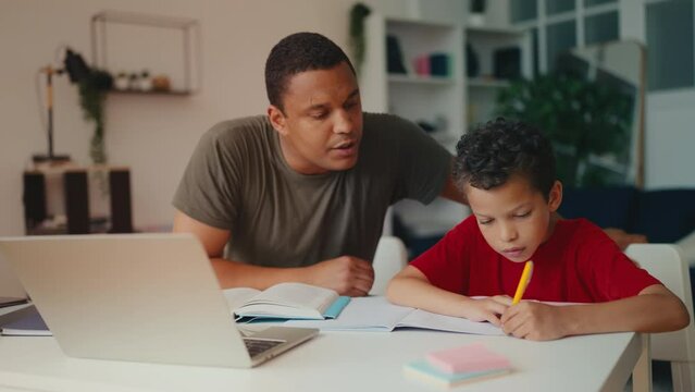 African American father and son doing school homework together, family support