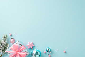 Luxurious festive gifts in aqua and blush with decorative accents. Overhead shot of ornate ornaments, present tied with pink ribbon, frosty pine branch on pastel blue backdrop, space for your message