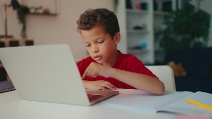 Little boy working on laptop pressing computer buttons, learning to use software