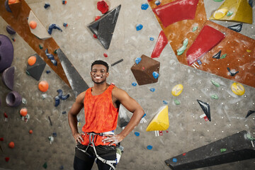 handsome african american man posing with alpine harness and hands on hips smiling at camera