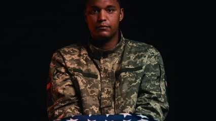 Sad serviceman holding triangle folded USA flag, tribute to fallen hero, funeral
