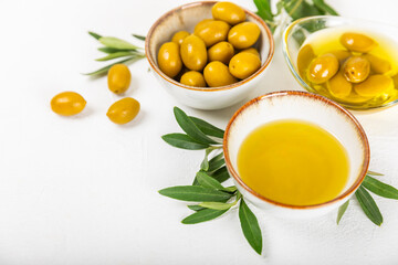 Olive oil in a bottle on texture background. Oil bottle and a bowl with branches and fruits of olives. Place for text. copy space. cooking oil and salad dressing.