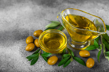 Olive oil in a bottle on texture background. Oil bottle and a bowl with branches and fruits of olives. Place for text. copy space. cooking oil and salad dressing.