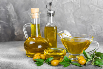 Olive oil in a bottle on texture background. Oil bottle and a bowl with branches and fruits of...
