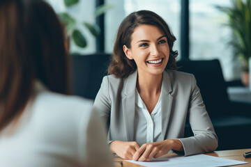 Happy businesswoman interviewing a job candidate in her office - obrazy, fototapety, plakaty