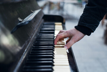 Close-up of a man's hands playing an old piano on the street, soft focus. Street musician