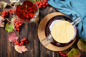 Autumn tea, berry vitamin seasonal drink. Viburnum and cup of healthy viburnum tea on a wood background. View from above.