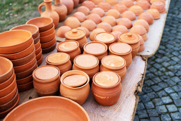 Fired clay pots and handmade plates on a counter at the market. Clay dishes