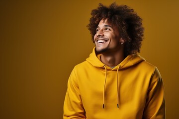 Fototapeta na wymiar Curly-haired male hipster freelancer in hoodie smiling studio photo