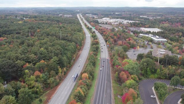 Drone footage over Donald Lynch Boulevard in Marlboro, Massachusetts. Traffic extends along both directions of highway, looking west. Fall foliage on trees to the horizon.