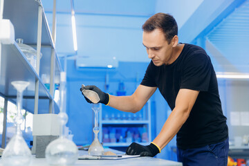 Engineer examines properties of river sand in flask to control quality of concrete, industrial laboratory of building materials