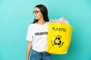 Young French girl holding a bag full of plastic bottles to recycle looking to the side