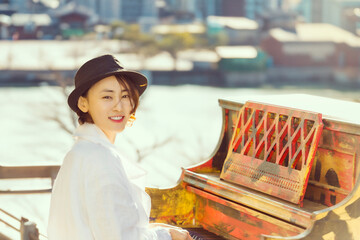 따뜻한 봄날 공원에 놓여진 피아노를 치고 있는 젊은 한국인 여성