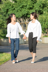 웃으며 손을 잡고 길을 걷고 있는 젊은 한국인 여성