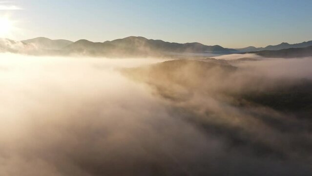 Aerial flight over the morning mist of Lika, Croatia. Flight over beautiful landscape with forest and grassland.