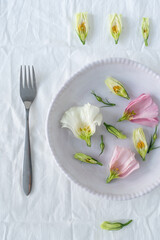 Decor of flowers and dishes on a white tablecloth. Pink and white flowers on fabric.