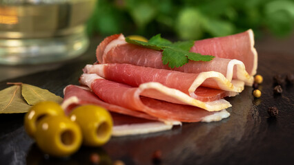 Fresh slices cured jamon on stone board with olives and parsley. Meat balyk pork. Cold cuts. Food. Spanish cuisine